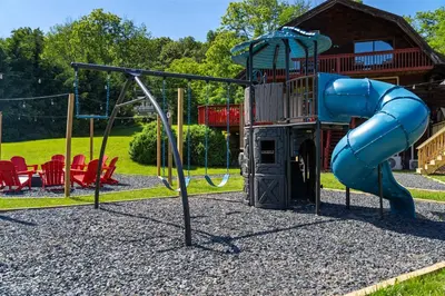 a playground with a blue slide in a park at 5BR Lux Cabin w HotTub Sauna Pool FirePit GameRoom in East Stroudsburg