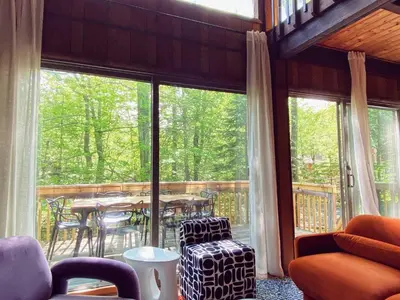 a screened in porch with a table and chairs at Designer Poconos Chalet I Ski, Skate, Lakes, Family-Friendly in Lake Ariel