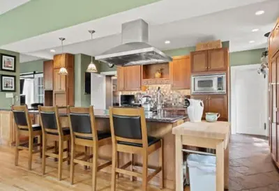 a kitchen with wooden cabinets and a bar with chairs at Majestic Family Home in Saratoga New York in Saratoga Springs