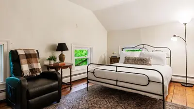 a bedroom with a bed and a chair at Pondfront Gem Minutes from Hudson’s Best Shops Cafes The Stillwater House in Hudson