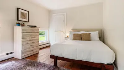 a bedroom with a white bed and a dresser at Pondfront Gem Minutes from Hudson’s Best Shops Cafes The Stillwater House in Hudson