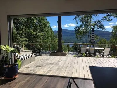 a deck with a view of the mountains through a window at House 15 mins from Woodstock NY with stunning views in Shokan