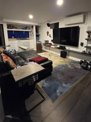 a living room with a black couch and a flat screen tv at House 15 mins from Woodstock NY with stunning views in Shokan