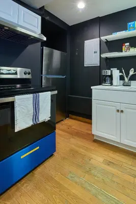 a kitchen with black and white appliances and wooden floors at The Luxe Loft in Long Island City