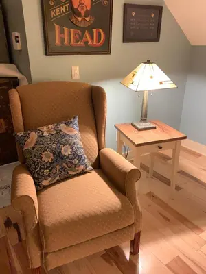 a living room with a chair and a table with a lamp at Apartment on the Battenkill River in Greenwich