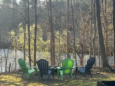 four chairs and a table in front of a lake at Tiny House on the Battenkill River in Greenwich