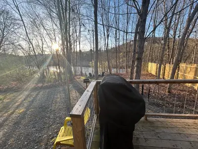 a person with a black cover on a wooden deck at Tiny House on the Battenkill River in Greenwich