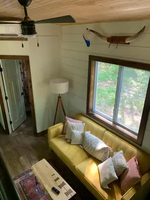 a living room with a couch and two windows at Tiny House on the Battenkill River in Greenwich