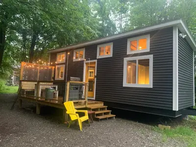 a black tiny house sitting on top of a wooden platform at Tiny House on the Battenkill River in Greenwich