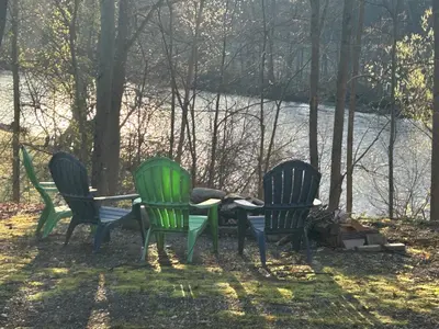 three green chairs and a table next to a river at Tiny House on the Battenkill River in Greenwich