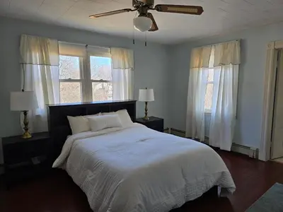 a bedroom with a large white bed with two windows at Captain Tiffany's in Saugerties