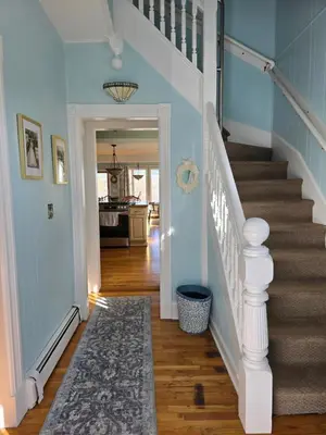 a hallway with blue walls and stairs with a rug at Captain Tiffany's in Saugerties