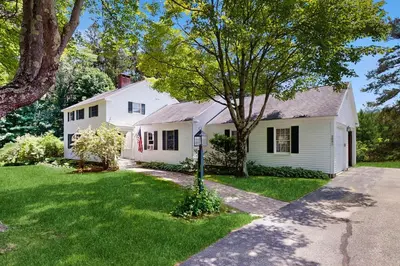 a white house with a tree in the yard at The Village House in Manchester