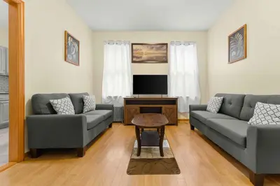 a living room with two couches and a tv at Immaculate furnished 1-Bedroom Apartment in Sunnyside
