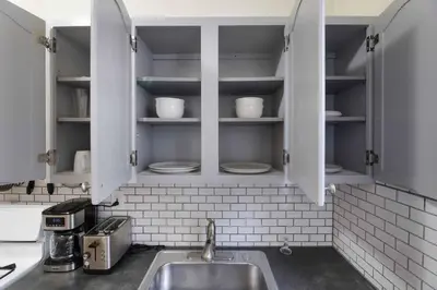 a kitchen with a sink and shelves with dishes at Immaculate furnished 1-Bedroom Apartment in Sunnyside
