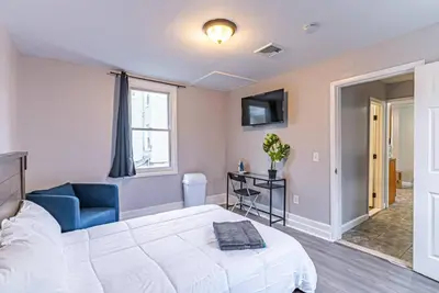 a bedroom with a white bed and a blue chair at Private BR Trains EWR USA Mall Penn Station in Newark