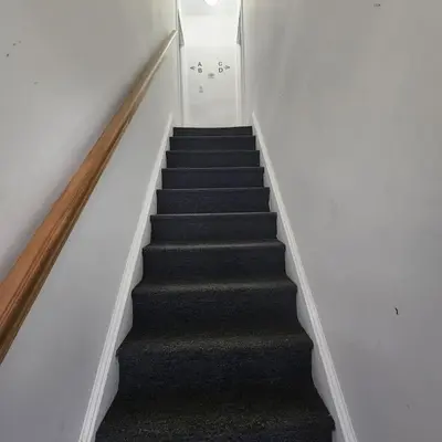 a staircase with black carpet and white walls at Private Bedroom In Shared Apt C in South Hackensack