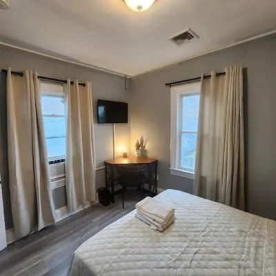 a bedroom with a bed and a table and windows at Bus Train 2 NYC Spacious 4BR SH in South Hackensack