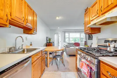 a kitchen with wooden cabinets and a sink and a table at 2 Blocks to Beach Walkable Woodmont Village Home in Milford