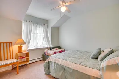 a bedroom with a bed and a chair and a window at 2 Blocks to Beach Walkable Woodmont Village Home in Milford