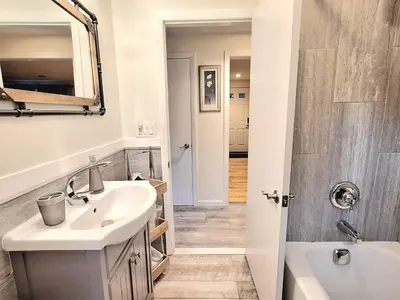 a bathroom with a sink and a mirror and a tub at 5•Star Fave CapeCodStyle Gem with Bedroom on Main in New Britain