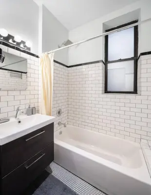 a white bathroom with a tub and a sink at Spacious 4Bd with Backyard in Manhattan in New York