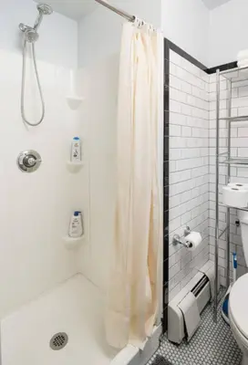 a white bathroom with a shower and a toilet at Spacious 4Bd with Backyard in Manhattan in New York
