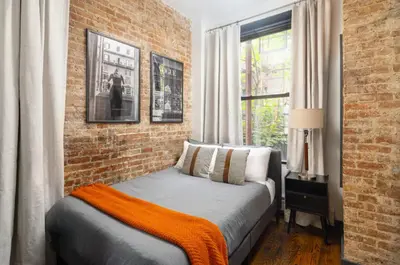 a bed in a room with a brick wall at Spacious 4Bd with Backyard in Manhattan in New York