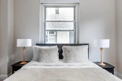 a bedroom with a bed with two lamps and a window at Blueground Lenox Hill view nr Central Park NYC-1303 in New York