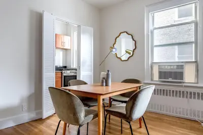 a dining room with a wooden table and chairs at Blueground Lenox Hill view nr Central Park NYC-1303 in New York