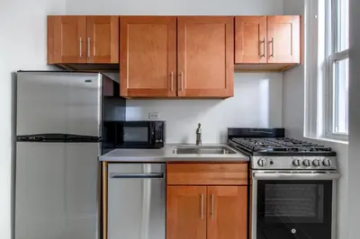 a kitchen with a sink and a stove and cabinets at Blueground Lenox Hill view nr Central Park NYC-1303 in New York