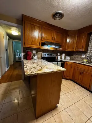 a kitchen with wooden cabinets and a granite counter top at Cozy Home in New Britain