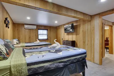 two beds in a room with wooden walls at Bear Haven Cabin - Epic Game RoomLakeFire Pit in Gouldsboro