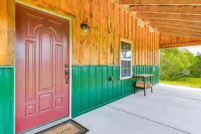 a barn with a red door and a bench on the porch at Escape to Nature Secluded McDonough Cabin!