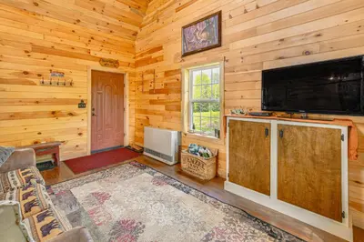 a living room with a large flat screen tv in a log cabin at Escape to Nature Secluded McDonough Cabin!