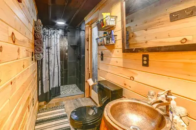 a bathroom with a sink in a wooden room at Escape to Nature Secluded McDonough Cabin!