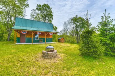 a small house with a green roof in a field at Escape to Nature Secluded McDonough Cabin!