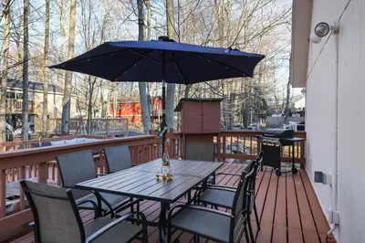 a table and chairs with an umbrella on a deck at The Cozy Modern Cabin Ski & Relax in Tobyhanna