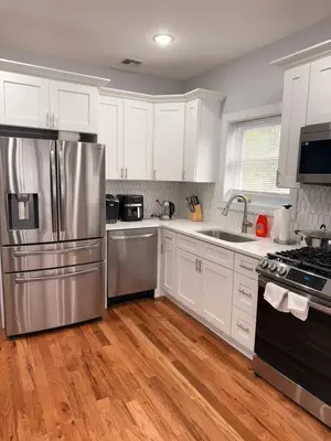 a kitchen with white cabinets and a stainless steel refrigerator at The great homes in East Orange