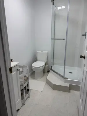 a white bathroom with a shower and a toilet at Ultra Contemporary Loft in Scarsdale
