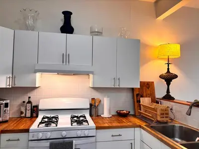 a kitchen with white cabinets and a stove and a sink at private spacious apartment with 2 bedrooms 2 bathroomss and a deck in New York