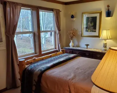 a bedroom with a large bed and a window at Serendipity Lake House in Windham