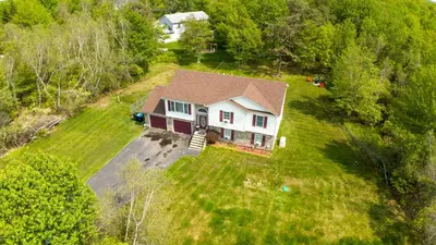 an aerial view of a house in the grass at Joy Cabin Where Family Friends Make Memories in Long Pond