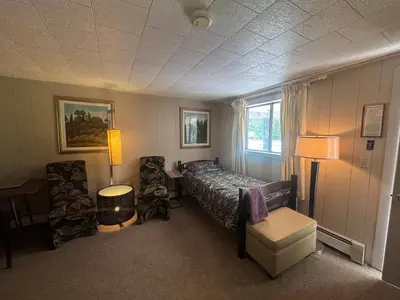 a bedroom with a bed and two chairs and a lamp at West Wind Motel in Fleischmanns