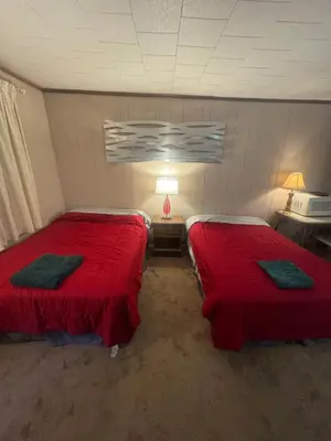 two beds in a room with red sheets at West Wind Motel in Fleischmanns