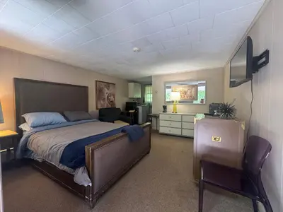 a bedroom with a bed and a desk and a chair at West Wind Motel in Fleischmanns