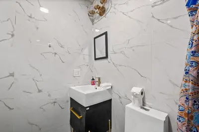 a bathroom with a sink and a white marble wall at 2 Queen Beds, TV's in Bedroom, Path to Manhattan in Jersey City