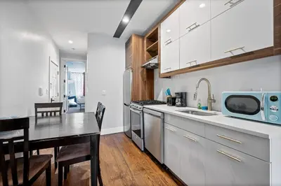 a kitchen with white cabinets and a table and a dining room at 2 Queen Beds, TV's in Bedroom, Path to Manhattan in Jersey City