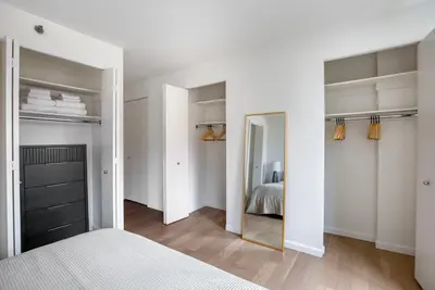 a bedroom with white walls and a mirror and a bed at Blueground Chelsea rooftop nr The High Line NYC-1201 in New York