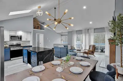 a dining room and living room with a dining table at Pocono Blue with Paddleboards, Spa, Indoor Jacuzzi, GameRoom, Lake, EV in Gouldsboro